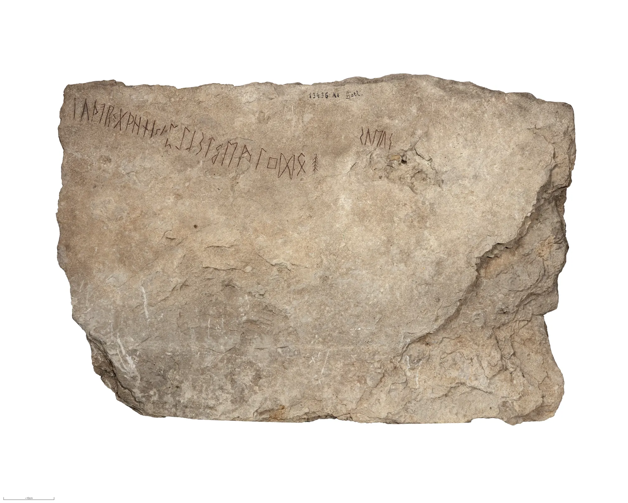 Gray limestone slab with a line of runes along its upper edge and a short word at upper right